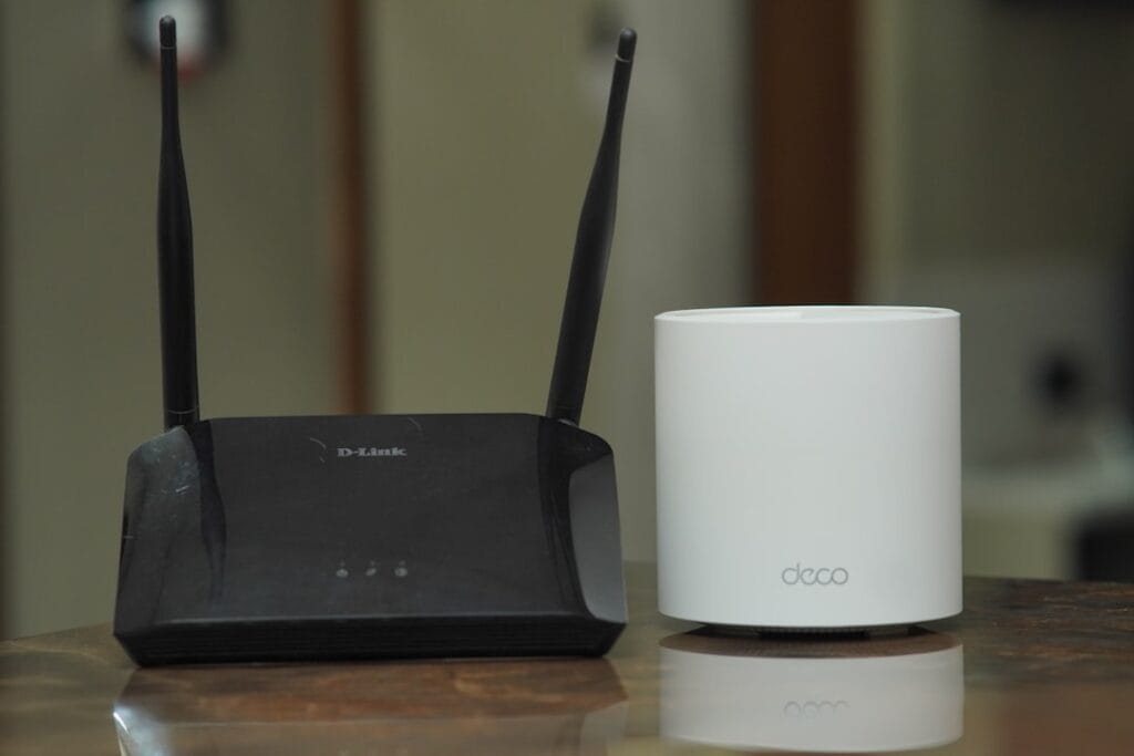 A traditional Wi-Fi router next to a modern mesh router. Many Miracast and AirPlay discovery failures trace back to router network configuration issues like AP isolation or mismatched Wi-Fi bands.