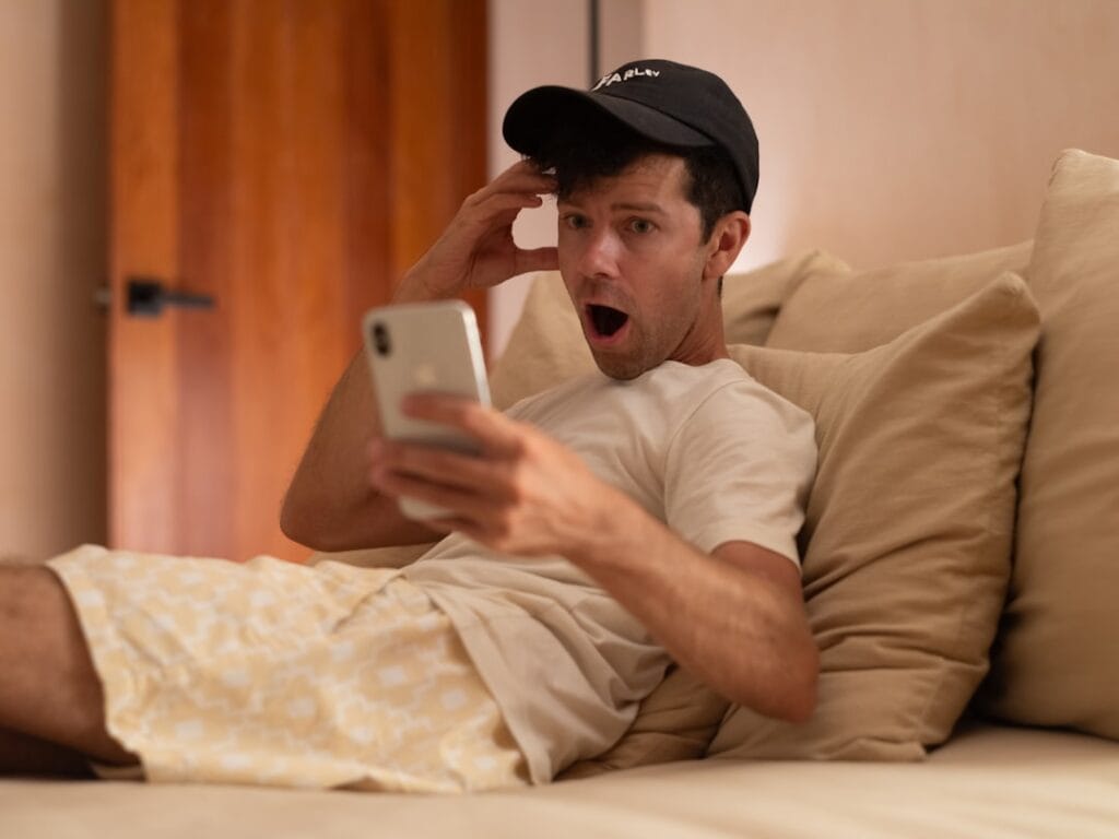 8 Free iPhone Video Editing Apps: No Watermark Test Shocked man looking at his smartphone screen, reacting to an unexpected paywall or watermark on a free video editing app
